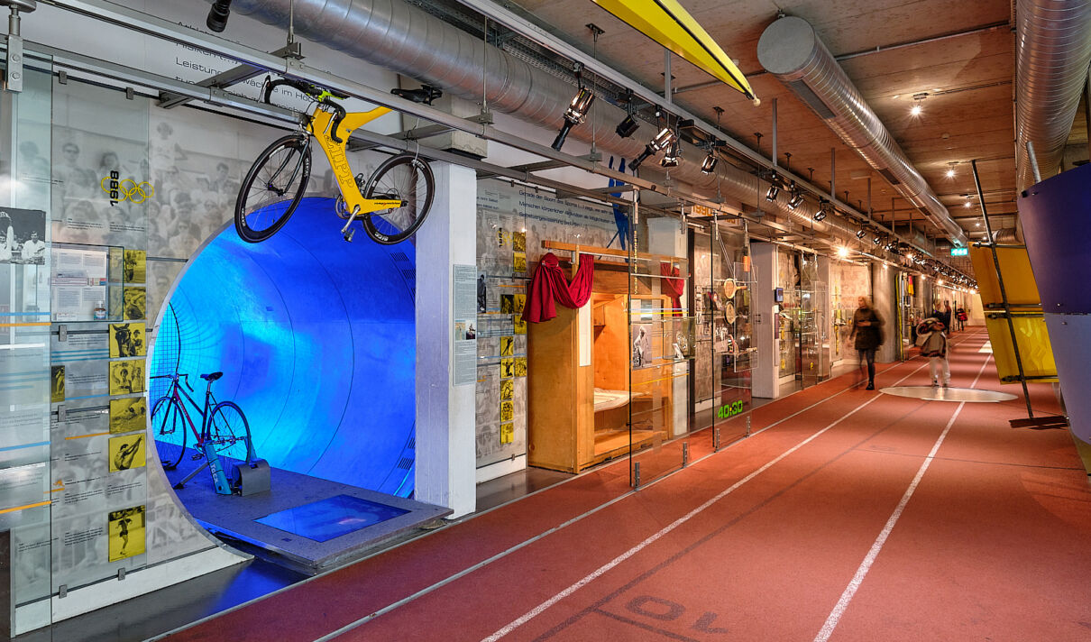 Das Foto zeigt einen Gang mit Ausstellungstücken im Deutschen Sport & Olympia Museum.