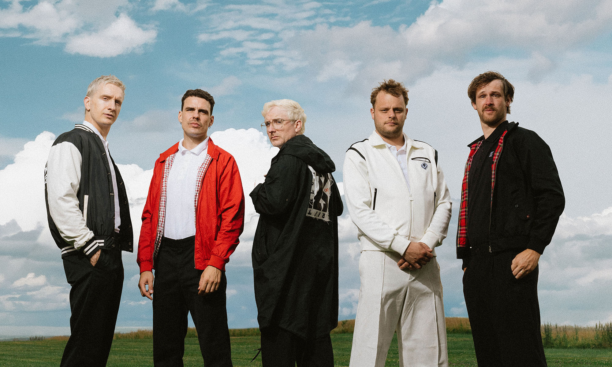 Die fünf Musiker der Chemnitzer Rockband Kraftklub, im hintergrunf blauer Himmel mit Wolken.