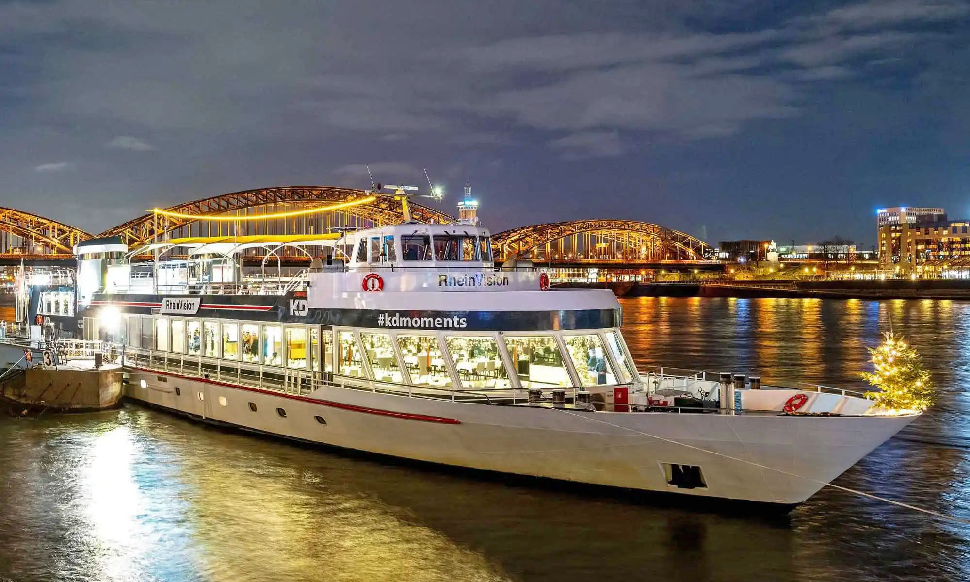 Die MS Rheinvision, ein Schiff der KD-Flotte, liegt beleuchtet am Anleger vor der Altstadt