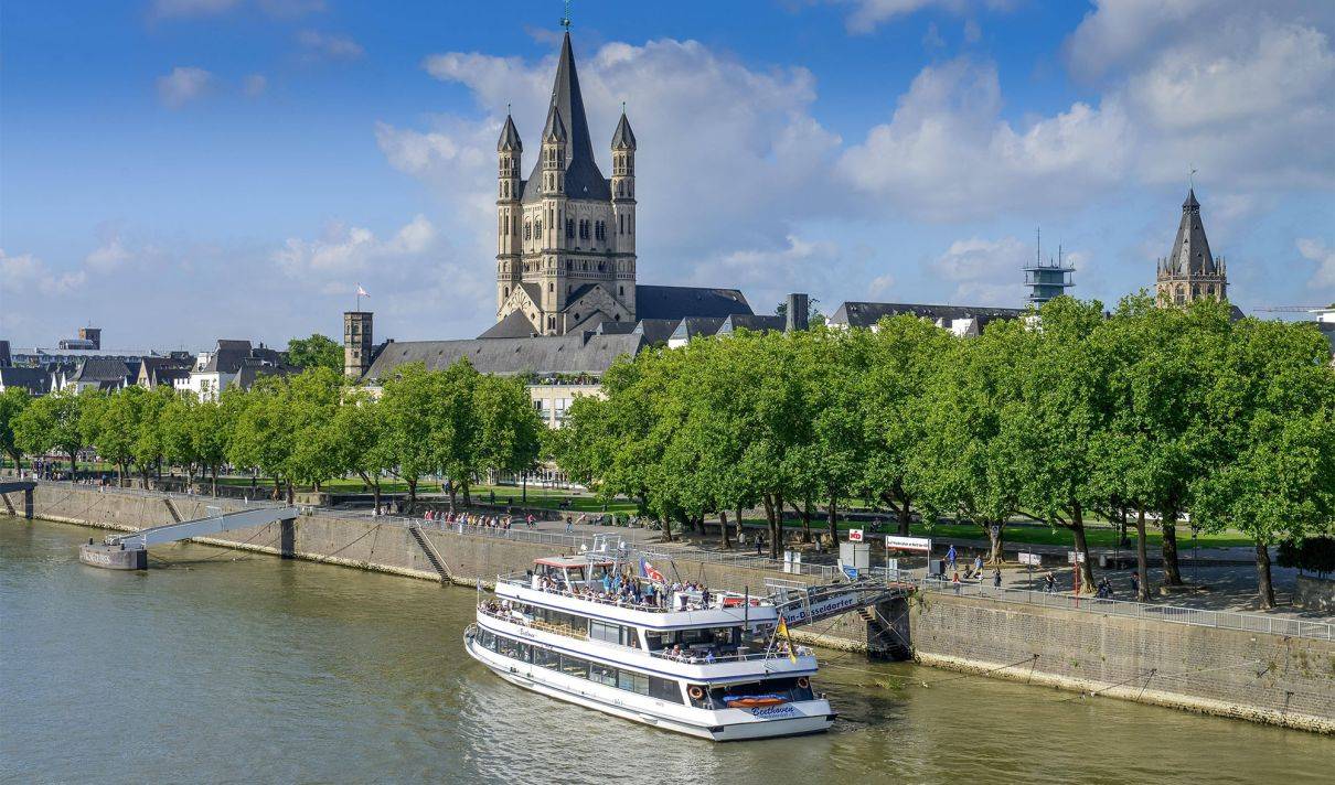 Schiffsanleger am Kölner Rheinufer mit der Altstadt sowie der Kirche Groß St. Martin im Hintergrund.