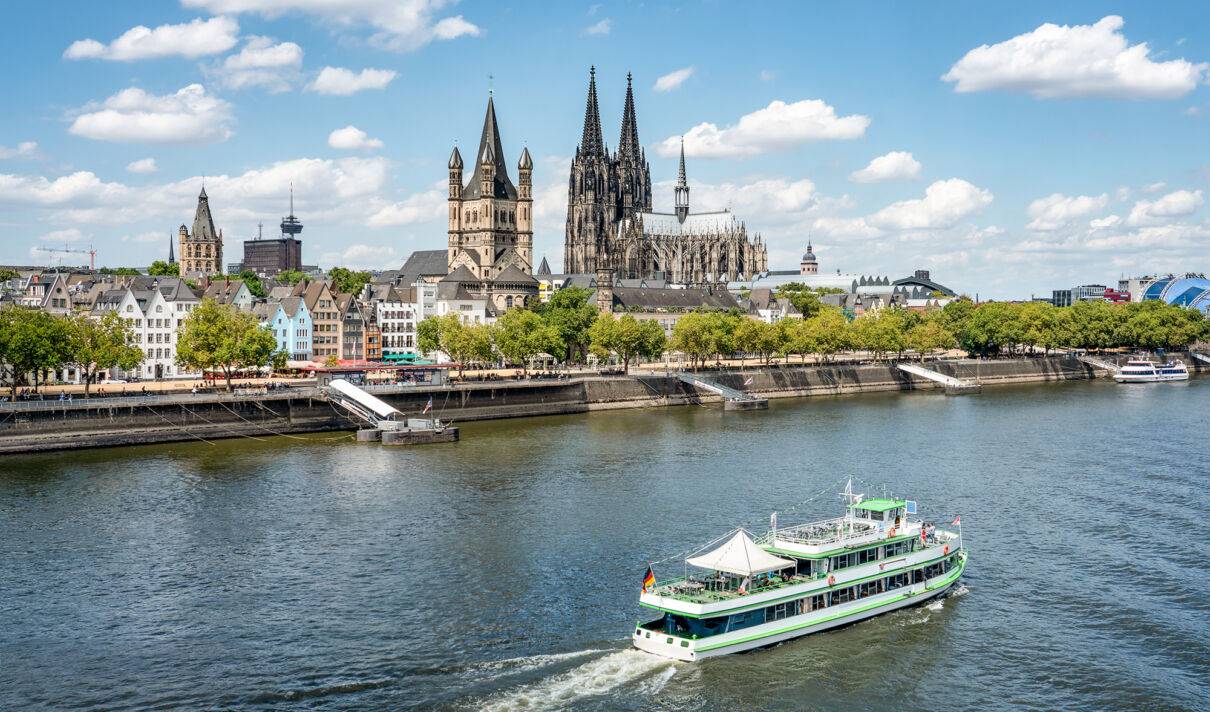 Kölner Dom, Groß St. Martin und die Kölner Altstadt, im Vordergrund ein Passagierschiff auf dem Rhein