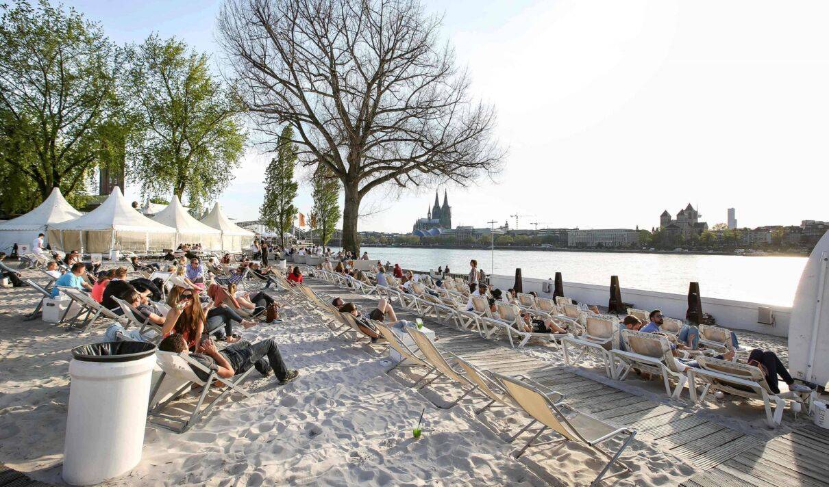 Menschen liegen auf Strandstühlen am Beachclub km689.